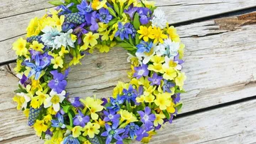 Blumenkranz liegt auf Holzoberfläche, farbenfroh und dekorativ.